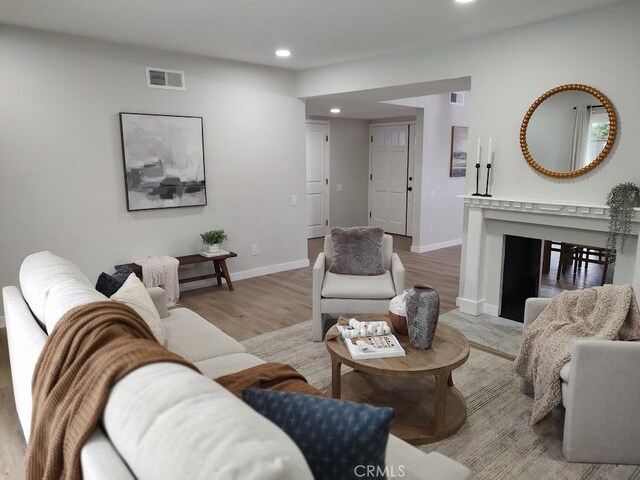 living room with recessed lighting, light wood-type flooring, visible vents, and baseboards