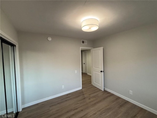 spare room with baseboards, visible vents, and dark wood-style flooring