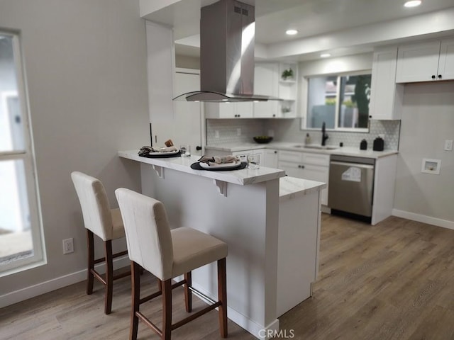 kitchen with island exhaust hood, a sink, white cabinetry, a peninsula, and dishwasher