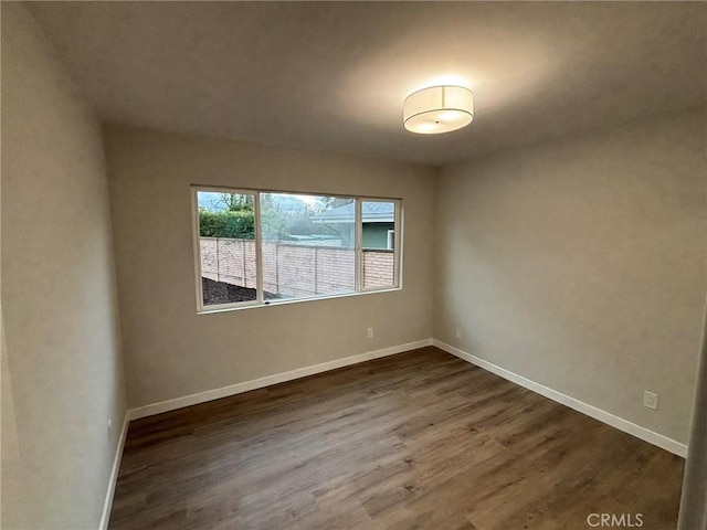 empty room featuring dark wood-style floors and baseboards