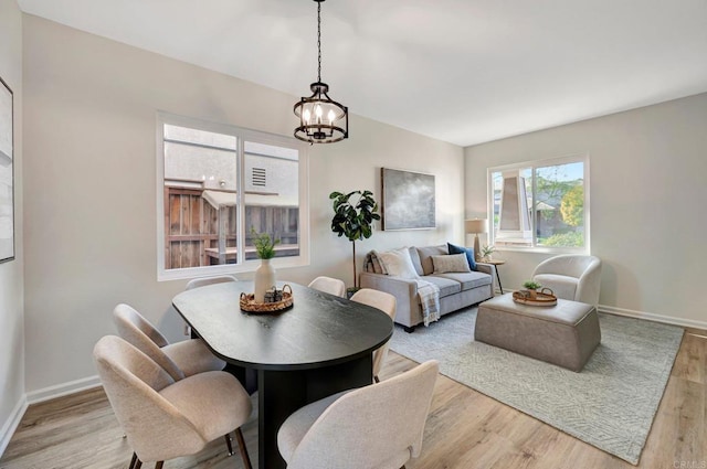 dining room featuring light wood-style floors, baseboards, and a chandelier