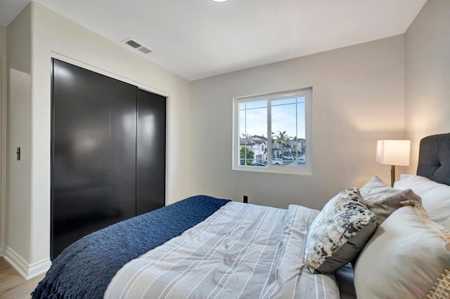 bedroom featuring a closet, visible vents, baseboards, and wood finished floors