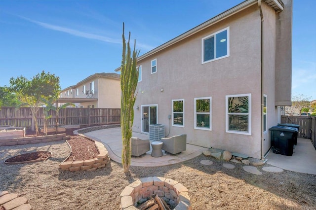 back of property featuring an outdoor fire pit, central AC unit, a fenced backyard, a patio area, and stucco siding