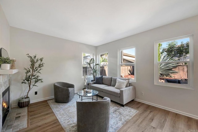 living area featuring light wood finished floors, a fireplace with flush hearth, and baseboards