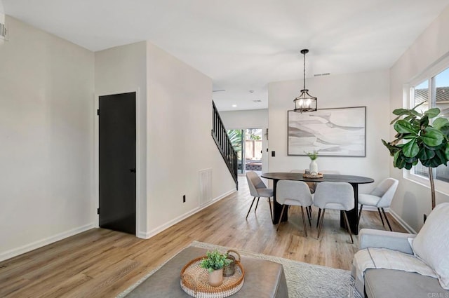 dining space with light wood-type flooring, visible vents, baseboards, and stairs