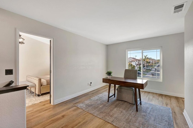 office featuring light wood finished floors, baseboards, visible vents, and a notable chandelier