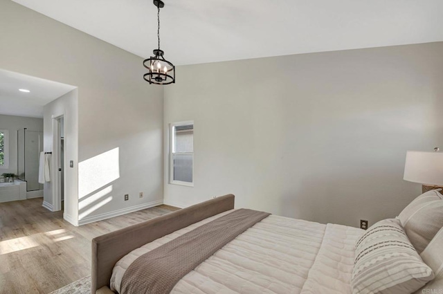 bedroom with baseboards, light wood finished floors, and an inviting chandelier