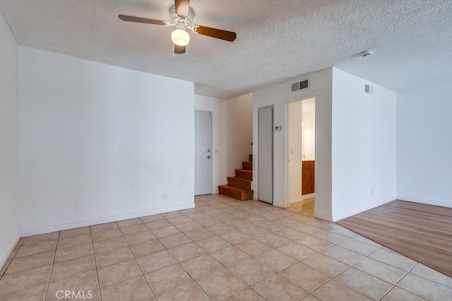 spare room featuring a ceiling fan, baseboards, visible vents, and a textured ceiling