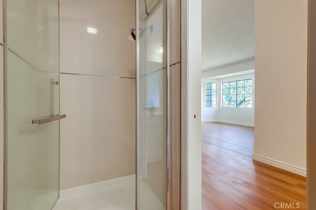 bathroom featuring baseboards, walk in shower, and wood finished floors