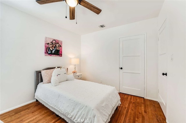 bedroom with ceiling fan, wood finished floors, visible vents, and baseboards