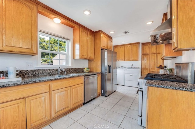 kitchen with visible vents, dark stone countertops, stainless steel appliances, ventilation hood, and washing machine and dryer