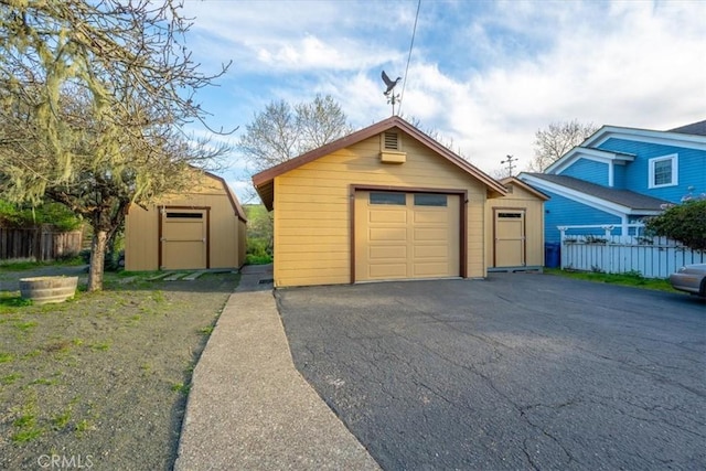 detached garage featuring aphalt driveway and fence