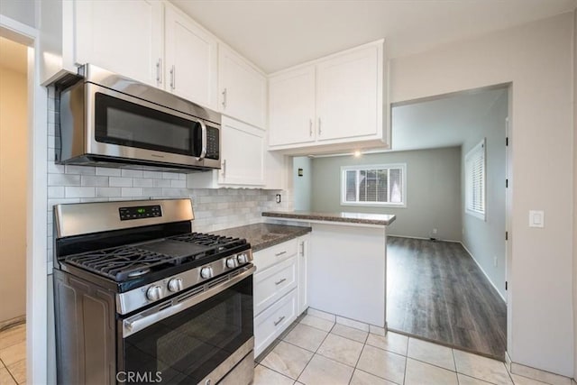 kitchen with light tile patterned floors, visible vents, stainless steel appliances, white cabinetry, and tasteful backsplash