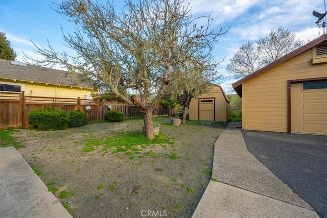 view of yard featuring a garage, a storage shed, an outdoor structure, and fence