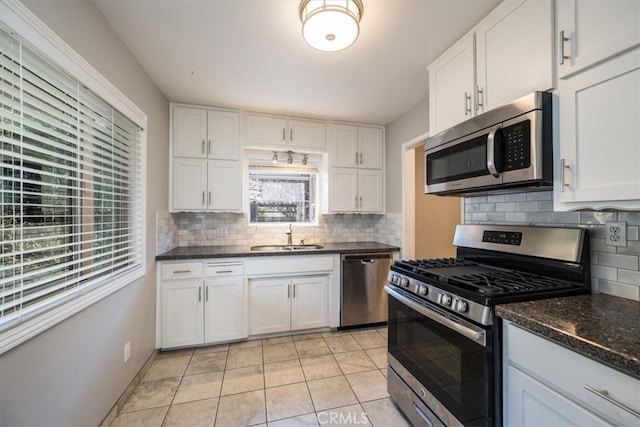 kitchen featuring light tile patterned floors, decorative backsplash, stainless steel appliances, white cabinetry, and a sink