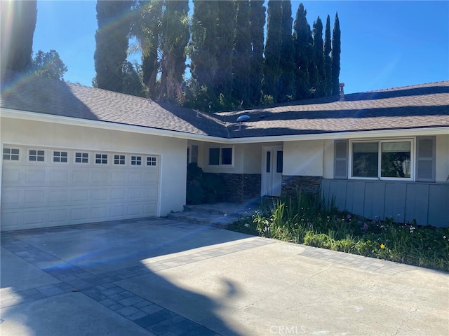 single story home featuring a garage, roof with shingles, driveway, and stucco siding