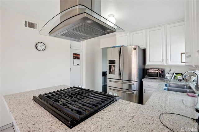 kitchen featuring island exhaust hood, white cabinetry, a sink, black gas stovetop, and stainless steel fridge