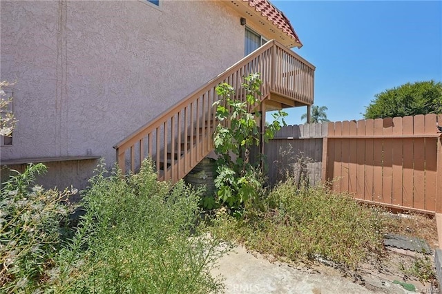 view of property exterior with stairs, fence, and stucco siding