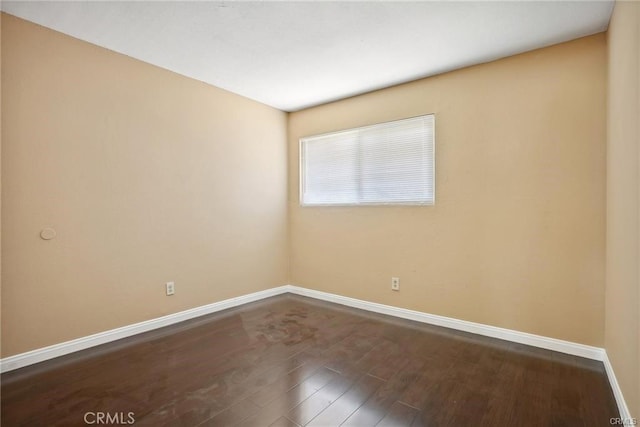 spare room featuring wood finished floors and baseboards