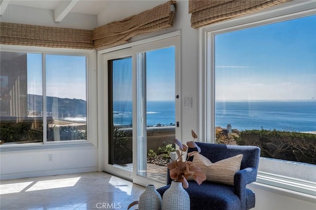 sunroom featuring a water view, plenty of natural light, and beam ceiling