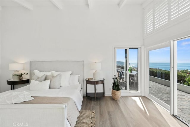 bedroom featuring access to exterior, beam ceiling, a water view, and multiple windows