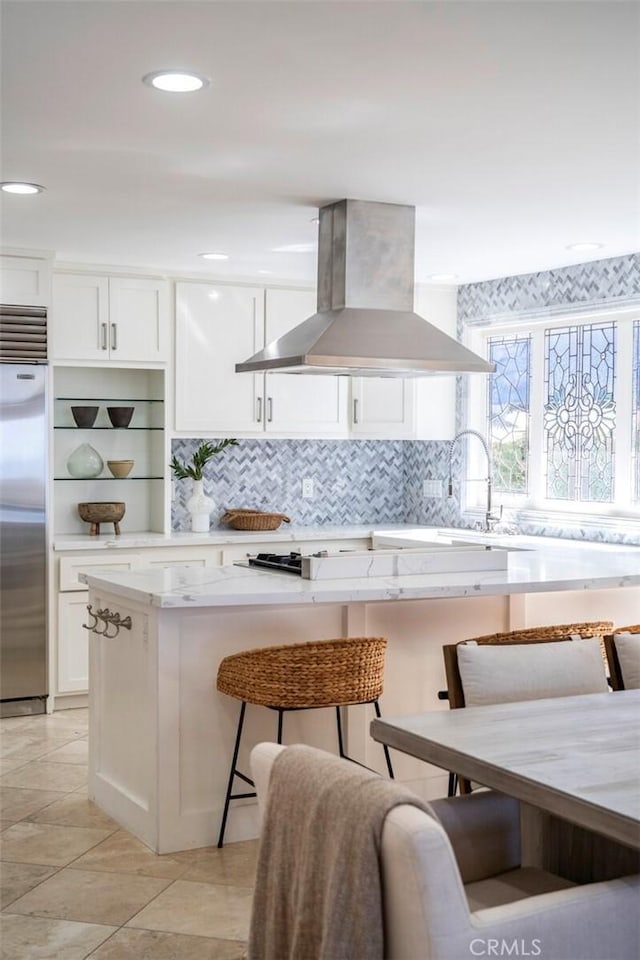 kitchen with stainless steel built in fridge, white cabinets, a center island, open shelves, and island exhaust hood