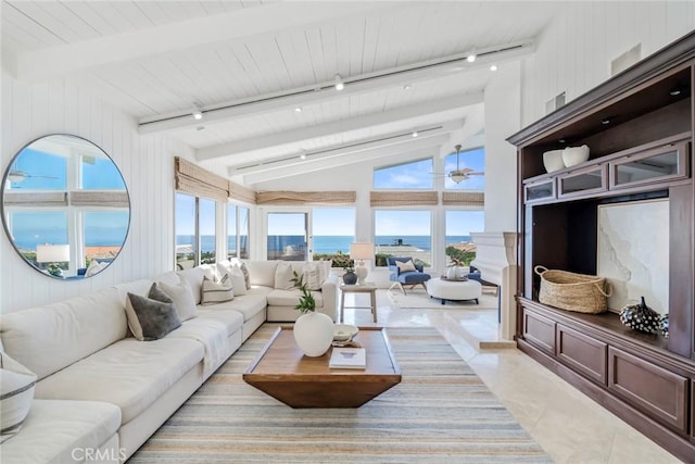 living area featuring light tile patterned floors, track lighting, a water view, and vaulted ceiling with beams