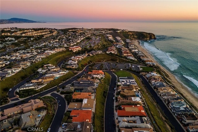 aerial view at dusk with a beach view and a water view