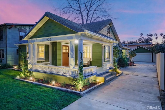 view of front facade with a garage, a front lawn, a porch, and an outdoor structure