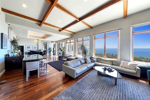 sunken living room with dark wood-style floors, beamed ceiling, a water view, and recessed lighting