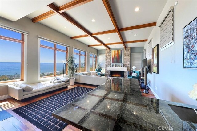 living room with a large fireplace, baseboards, coffered ceiling, wood finished floors, and a water view