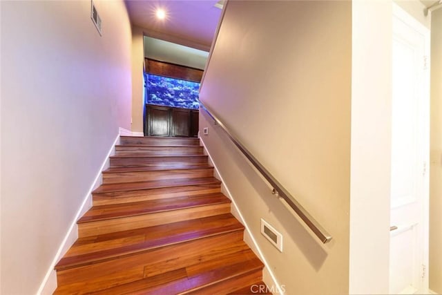 stairs with visible vents, baseboards, and wood finished floors