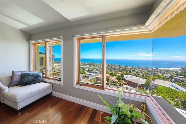 sitting room featuring a water view, wood finished floors, and baseboards