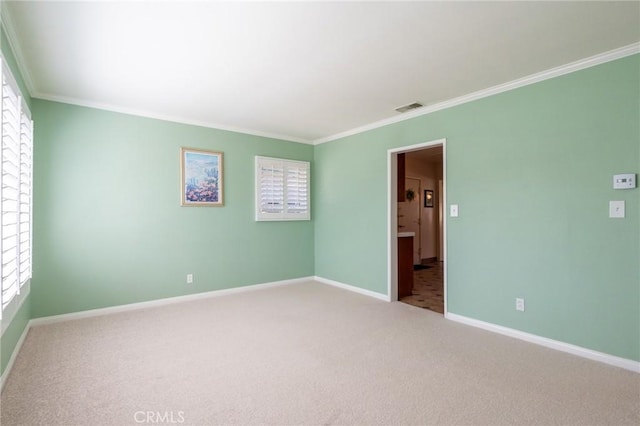 unfurnished room featuring crown molding, carpet flooring, baseboards, and visible vents