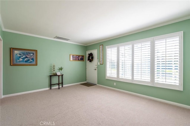 carpeted spare room with visible vents, baseboards, and ornamental molding