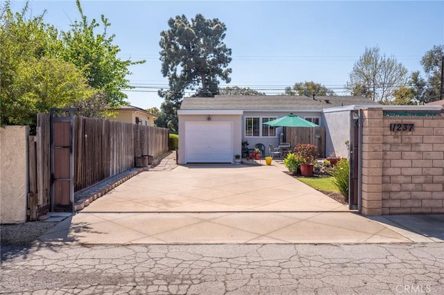 garage with a gate, concrete driveway, and fence