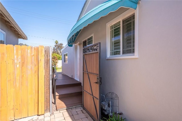 view of side of home with stucco siding and fence