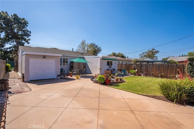 ranch-style house featuring a front lawn, fence, concrete driveway, stucco siding, and a patio area