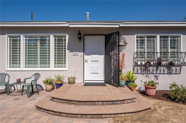 entrance to property with stucco siding and a patio