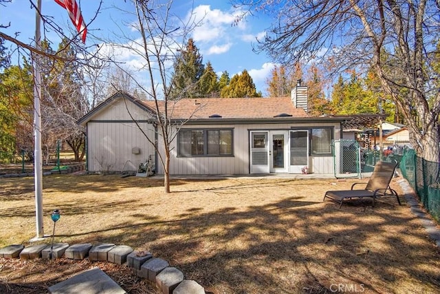 back of house featuring a yard, fence, and a chimney