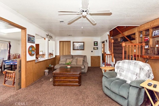 living room featuring stairs, wood walls, carpet, and a wainscoted wall