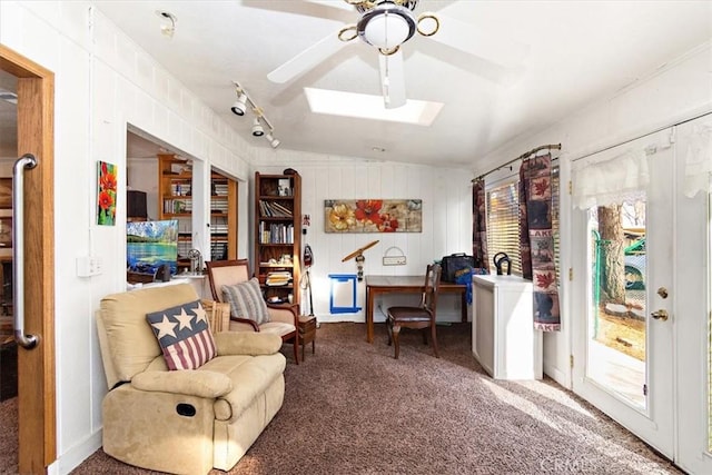 living area with a ceiling fan, carpet, and a skylight