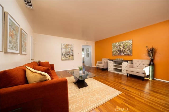 living area featuring visible vents and wood finished floors