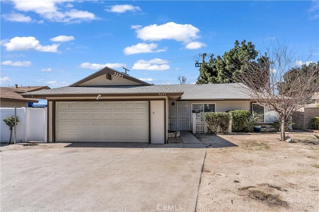 single story home with driveway, an attached garage, and fence