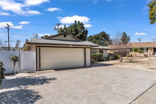 garage with concrete driveway and fence