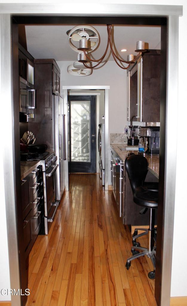 kitchen featuring appliances with stainless steel finishes, dark brown cabinetry, and light wood-style floors