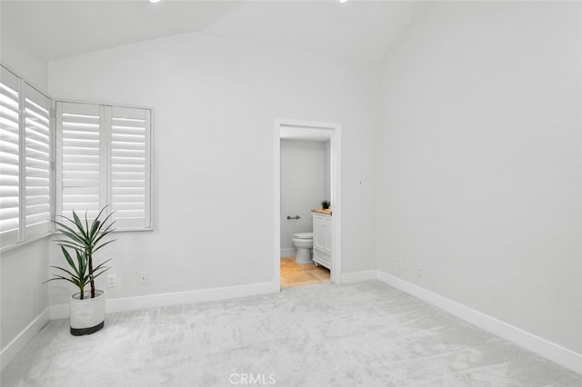 spare room with carpet floors, baseboards, and vaulted ceiling