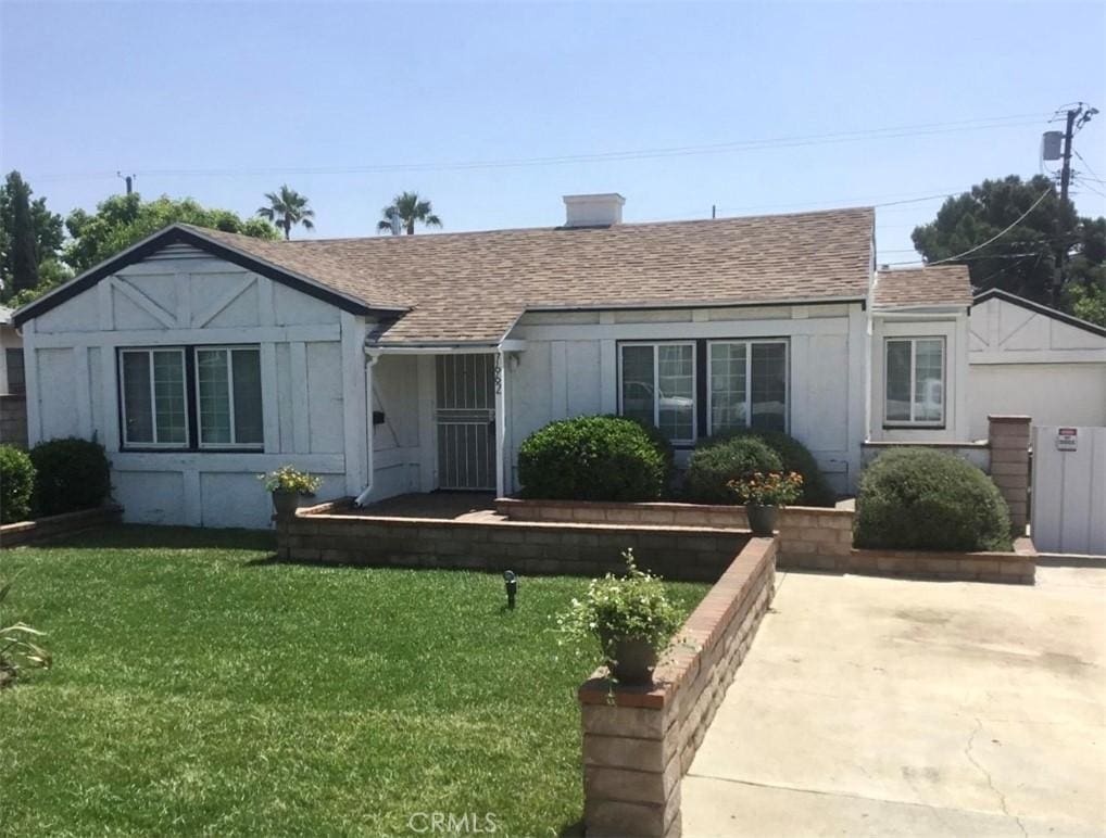 view of front of house with a shingled roof and a front yard