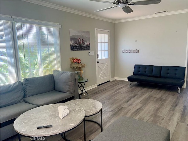 living room with a wealth of natural light, wood finished floors, visible vents, and crown molding