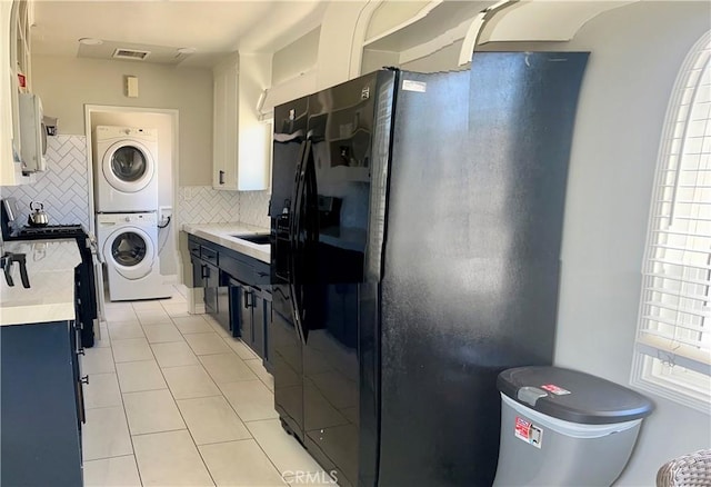 7662 Paso Robles Ave, Van Nuys, CA 91406 - kitchen featuring stacked washing maching and dryer, light countertops, light tile patterned floors, decorative backsplash, and black refrigerator with ice dispenser